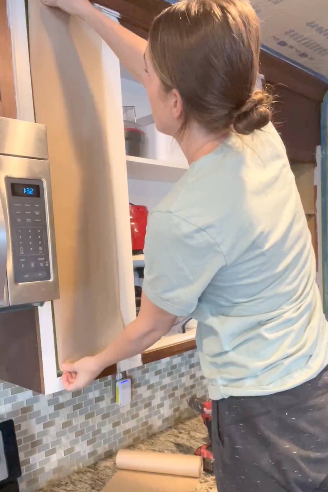 Masking off and papering the insides of the cabinets in order to protect it when using a paint sprayer with cabinet paint.